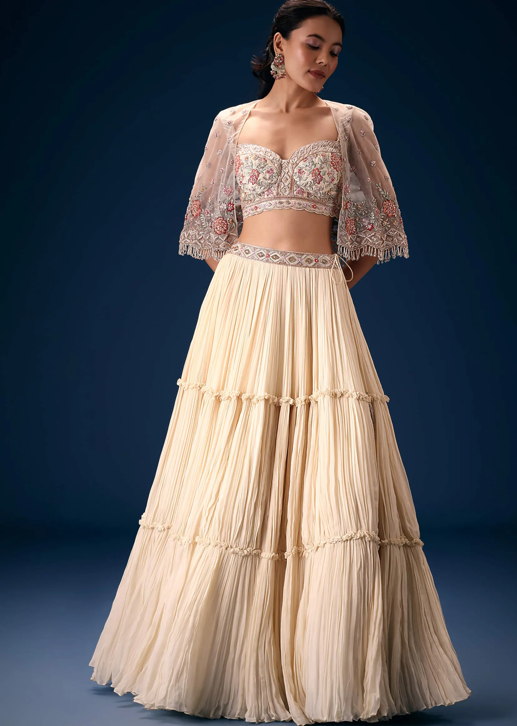 Off White Tiered Lehenga With Embroidered Corset Blouse And Embroidered Cape